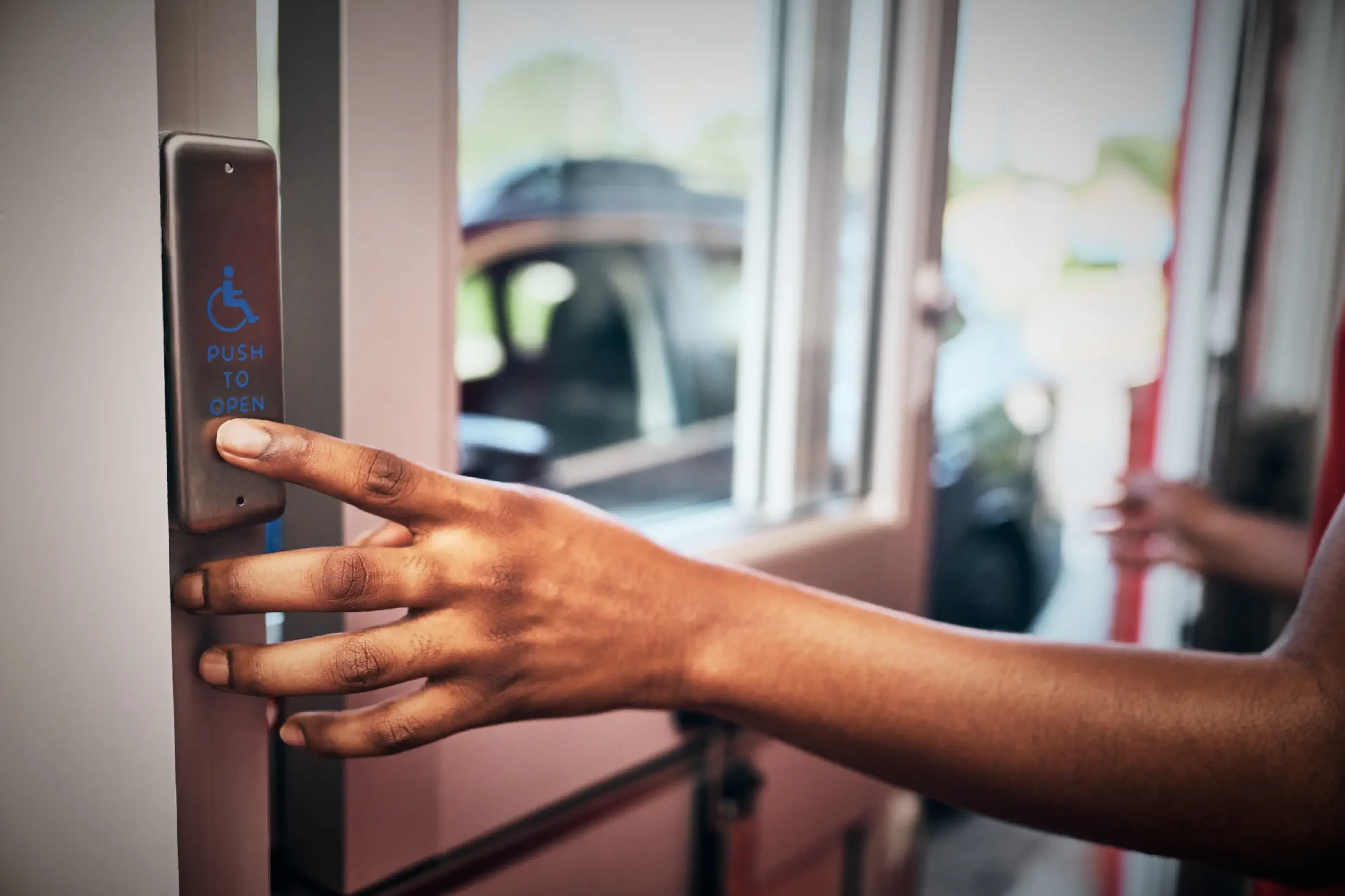 person pressing activation push plate on a drive thru door