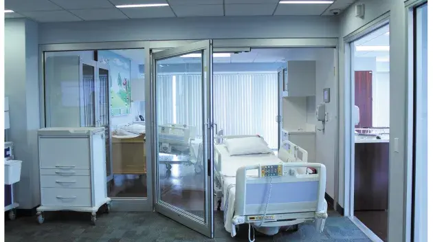 A hospital bed wheeling out of a set of doors.