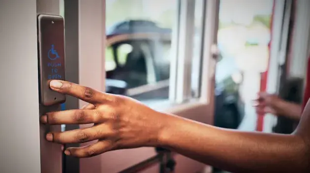 person pressing activation push plate on a drive thru door