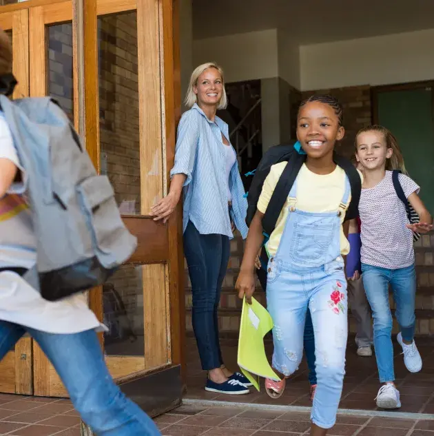 group of young children running out of school doors
