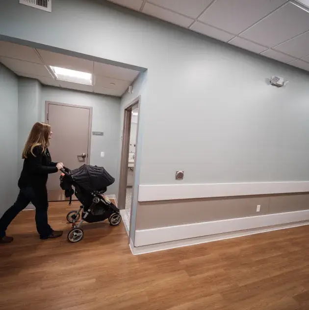 A person walking through a door with a stroller.