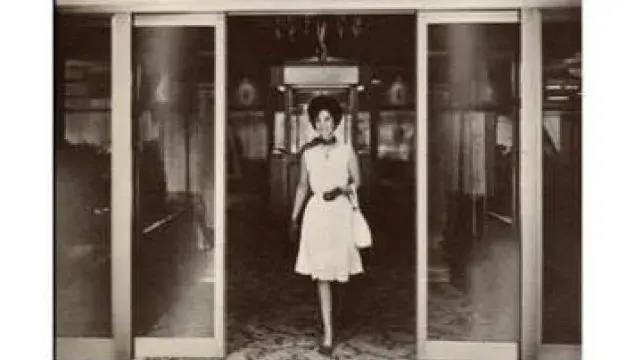 A woman walking through a sliding door.